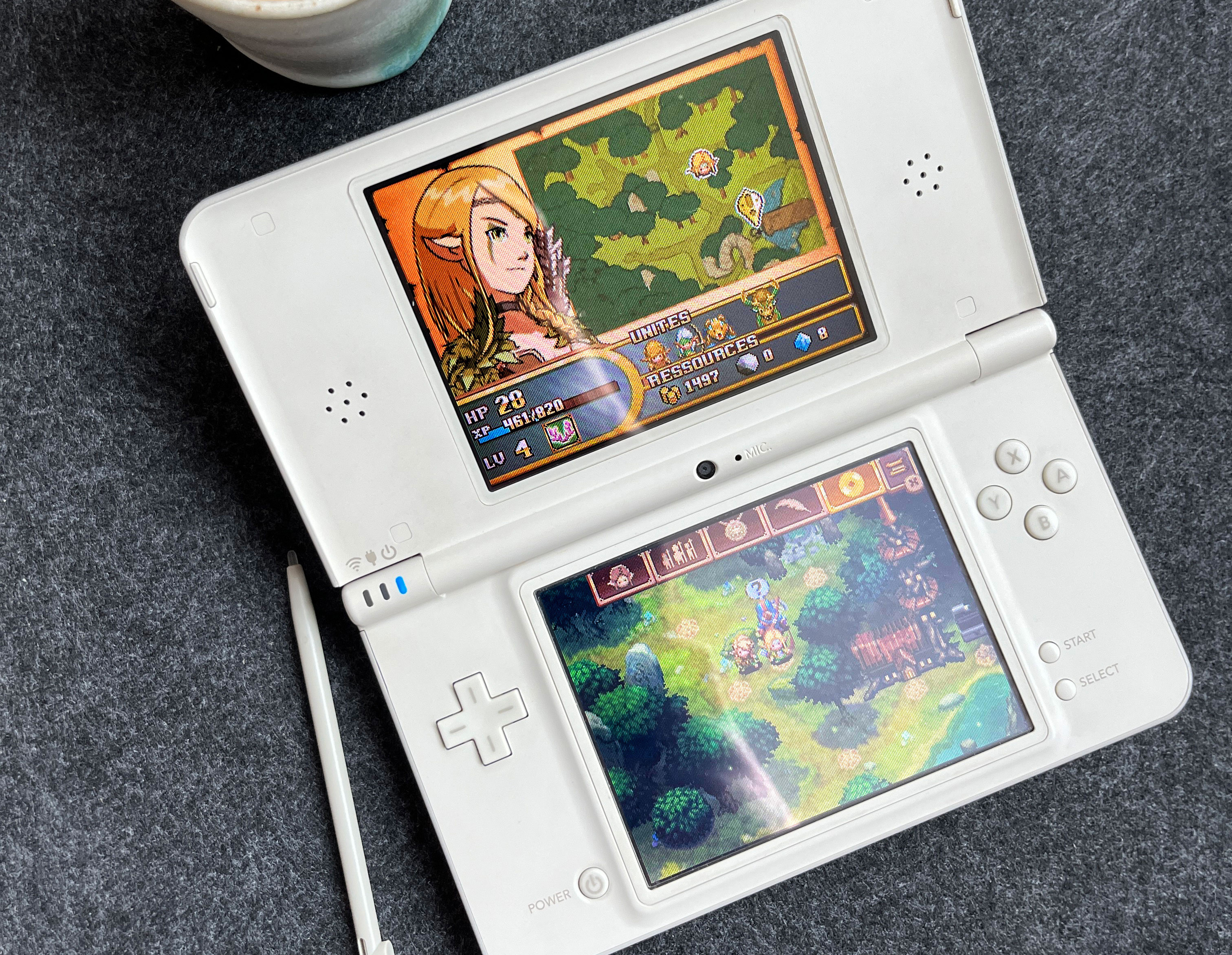 Fotografía de una consola Nintendo DS blanca con el juego Might & Magic: Clash of Clans corriendo